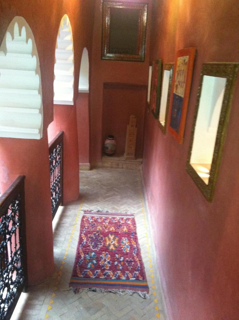 - un couloir avec un mur rouge et un tapis au sol dans l'établissement Riad Tarik, à Marrakech