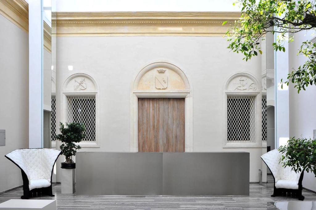 un hall d'entrée avec une porte en bois et deux chaises dans l'établissement Hotel Romano House, à Catane