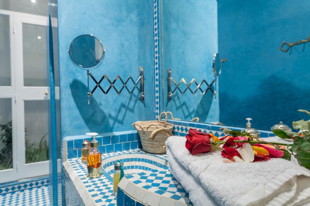 La salle de bains est pourvue de carrelage bleu et d'une baignoire avec 2 serviettes. dans l'établissement Astra Damus Hotel, à Marrakech