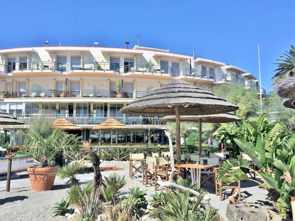 un hôtel avec des tables et des parasols devant lui dans l'établissement Hotel Tirreno, à Spotorno