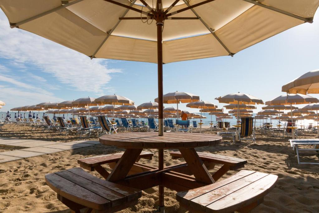 - une table de pique-nique et des bancs sur une plage avec des parasols dans l'établissement Hotel Miramare, à Pineto