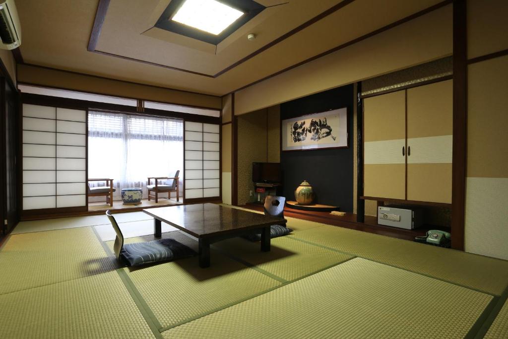 un salon avec une table et une fenêtre dans l'établissement Kaichoen, à Yonago 10 autres photos