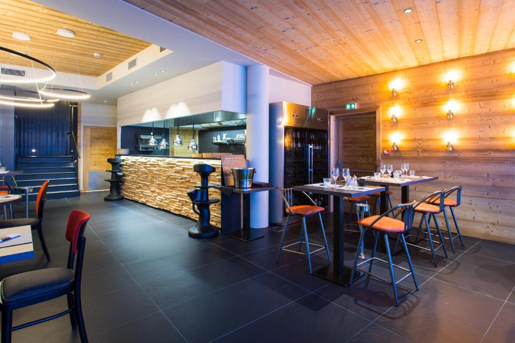 un restaurant avec des tables et des chaises et un bar dans l'établissement Hôtel Taj-I Mah by Les Etincelles, à Arc 2000