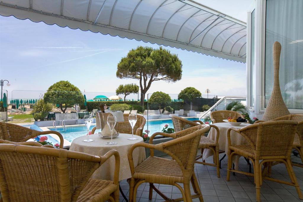 un patio avec tables et chaises et une piscine dans l'établissement Hotel Croce Di Malta, à Lido di Jesolo