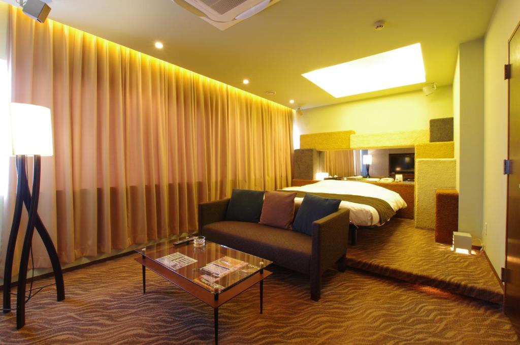une chambre d'hôtel avec un canapé et un lit dans l'établissement Blue Hotel Octa (Adult Only), à Sapporo
