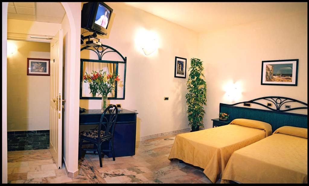 une chambre avec deux lits, un bureau et une télévision dans l'établissement Villa Gaia Hotel, à Cefalù