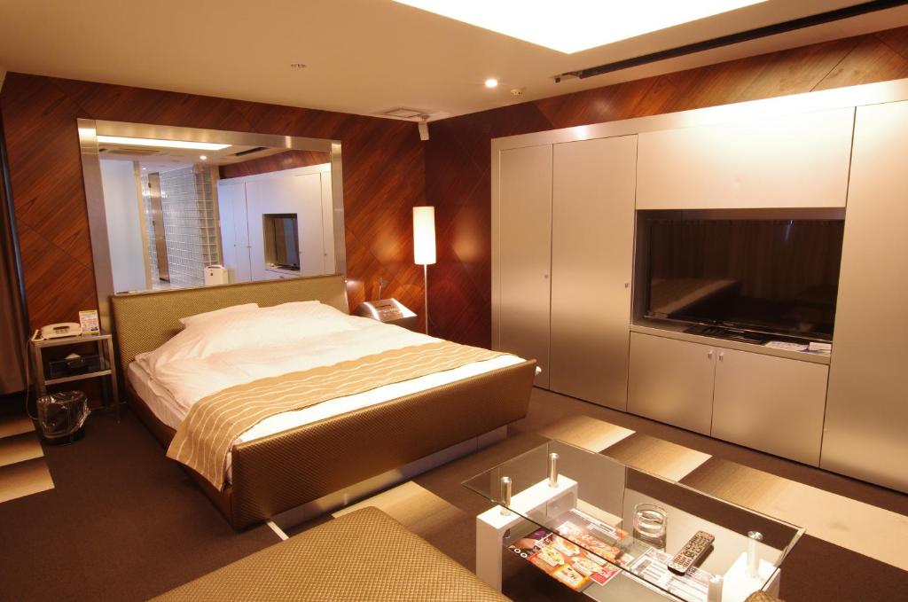 une chambre avec un lit et une télévision à écran plat dans l'établissement Blue Hotel Octa (Adult Only), à Sapporo