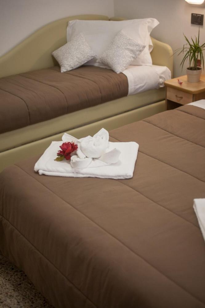 - une chambre d'hôtel avec 2 lits, des serviettes et des fleurs dans l'établissement Hotel Zurigo, à Rimini