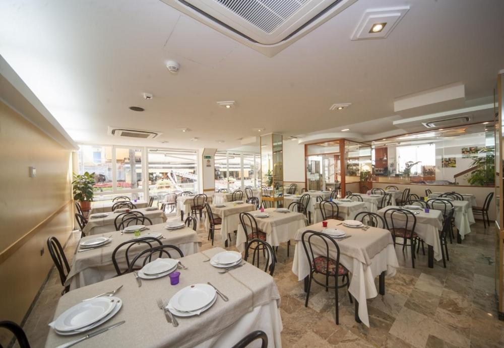 un restaurant avec tables et chaises et nappes blanches dans l'établissement Hotel Zurigo, à Rimini