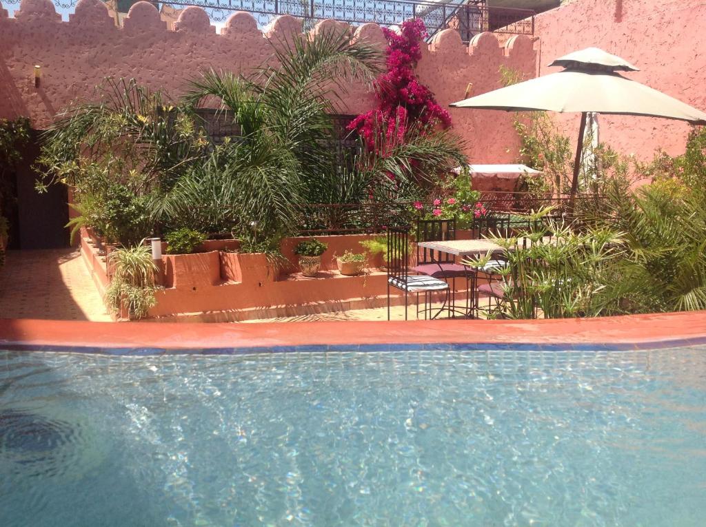 une piscine avec une table et un parasol dans l'établissement Riad El Ma, à Meknès 36 autres photos
