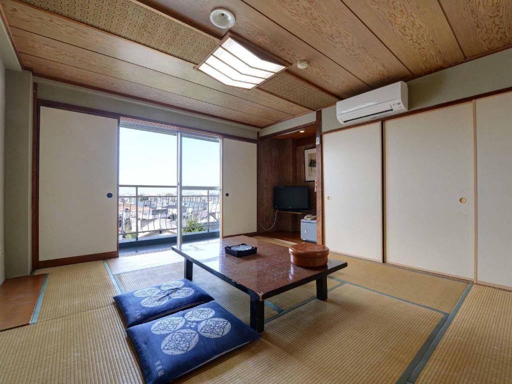 un salon avec une table et une grande fenêtre dans l'établissement Suisenkaku, à Numazu