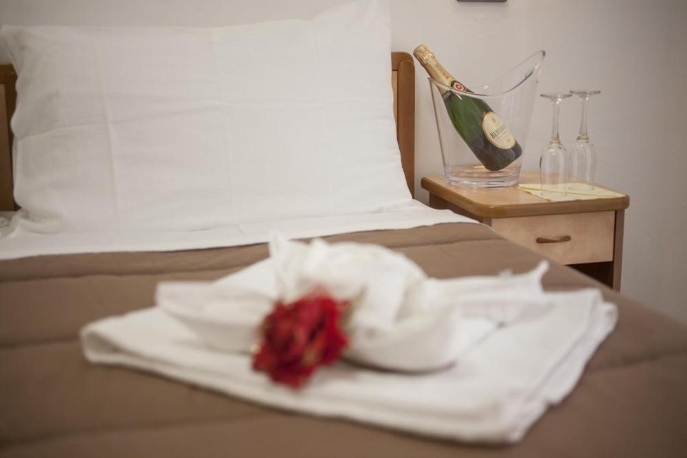 une plaque blanche avec une fleur rouge sur un lit dans l'établissement Hotel Zurigo, à Rimini