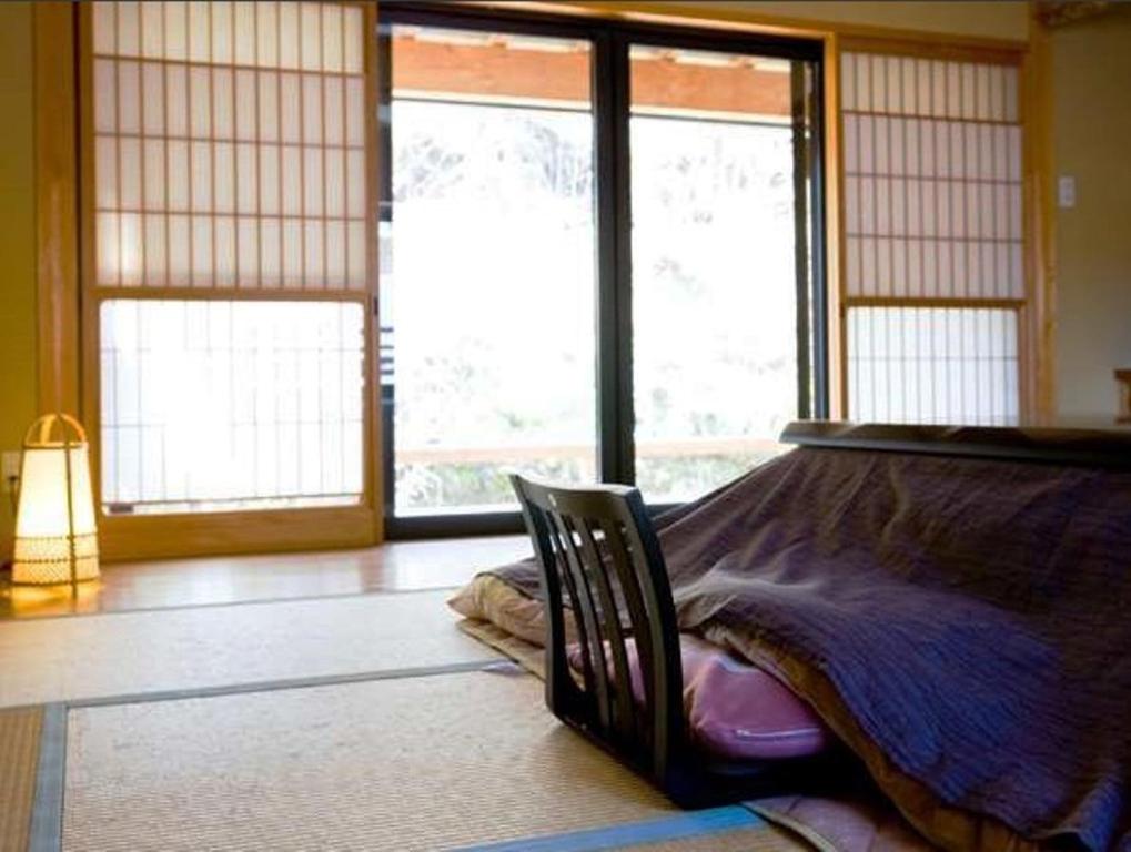 une chambre avec un lit dans une pièce avec des fenêtres dans l'établissement Hanaya Tokubei, à Tenkawa