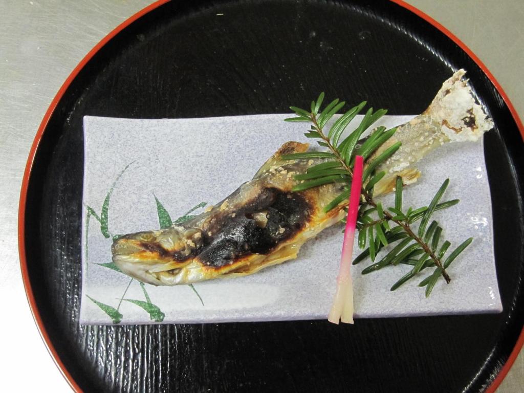 une plaque noire avec un morceau de nourriture sur une table dans l'établissement Suisensou, à Takayama