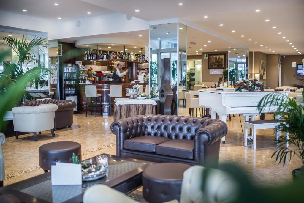 un hall avec des canapés, un bar et un piano dans l'établissement Hotel Excelsior, à Bibione