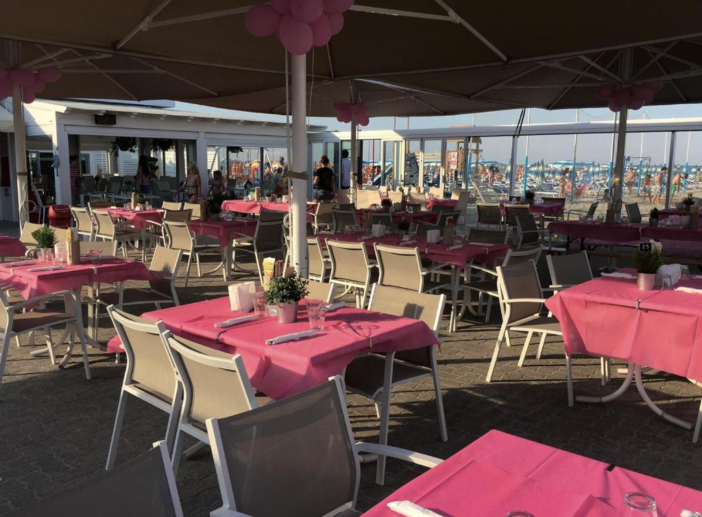 un groupe de tables et de chaises avec tissu de table rose dans l'établissement Hotel Riziana, à Cervia