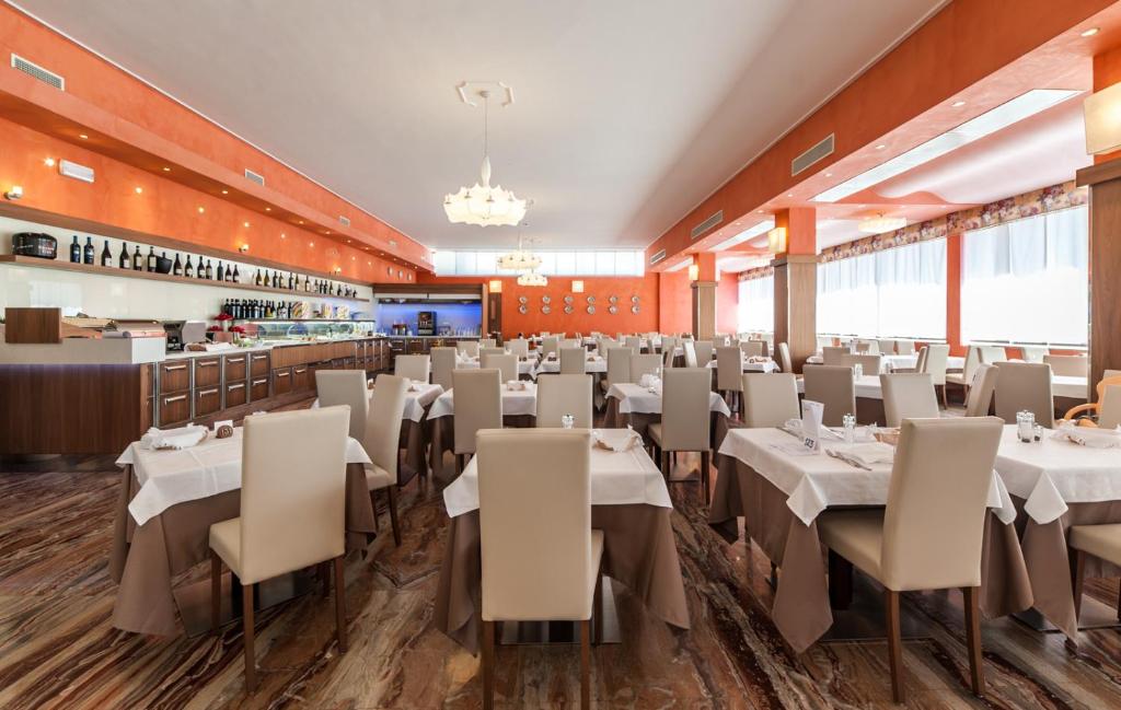 une salle à manger avec des tables et des chaises blanches dans l'établissement Hotel President, à Bibione
