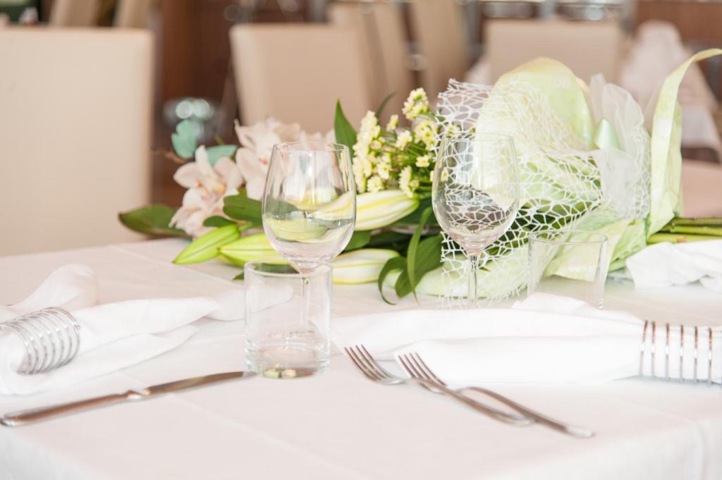 une table avec deux verres à vin et un bouquet de fleurs dans l'établissement Hotel President, à Bibione 70 autres photos