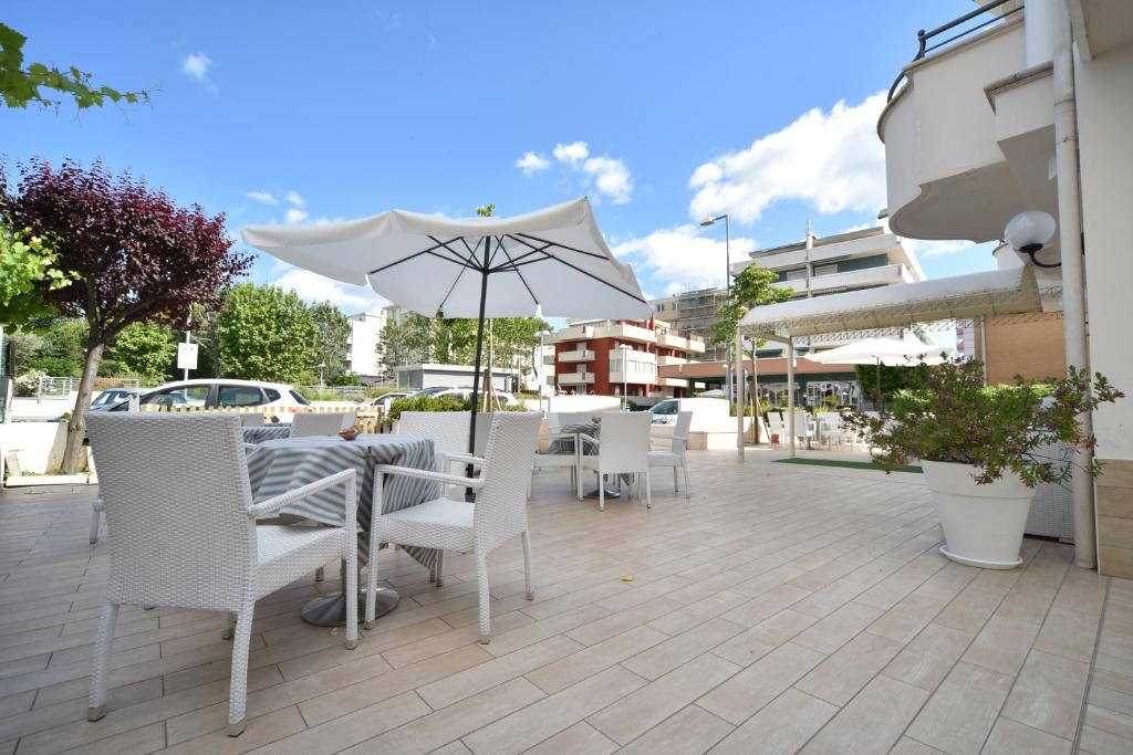 une table et des chaises avec un parasol sur une terrasse dans l'établissement Hotel Marina, à Riccione