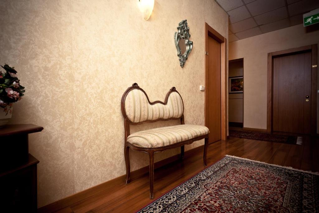 une chaise contre un mur dans un couloir dans l'établissement Phi Hotel Ambra, à Pescara