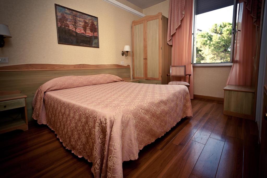 - une chambre avec un lit doté d'un couvre-lit rose et d'une fenêtre dans l'établissement Phi Hotel Ambra, à Pescara 41 autres photos