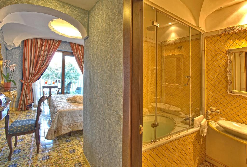 une salle de bain avec baignoire et une chambre avec un lit dans l'établissement Strand Hotel Delfini, à Ischia