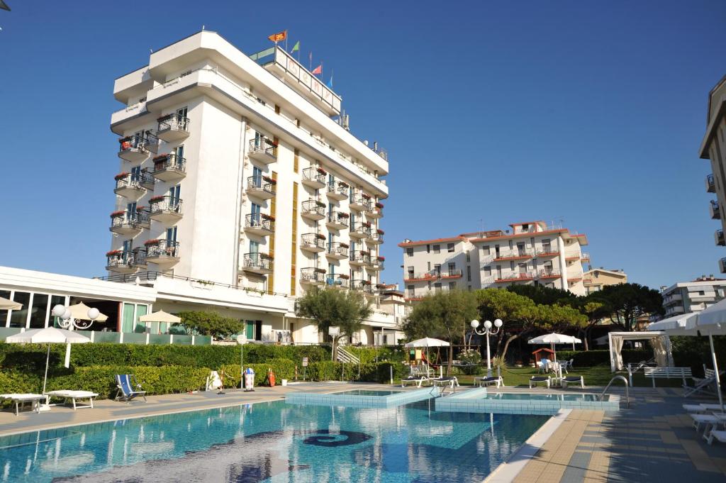 un hôtel avec une piscine devant un bâtiment dans l'établissement Hotel Beny, à Lido di Jesolo