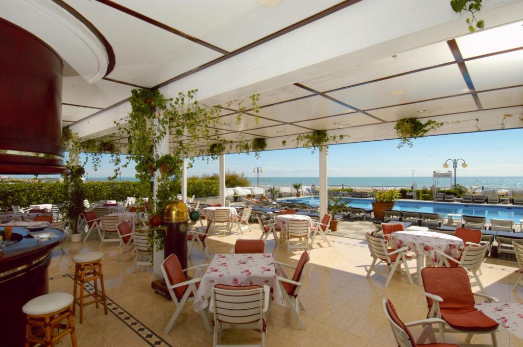 un restaurant avec des tables et des chaises et une piscine dans l'établissement Hotel Beny, à Lido di Jesolo