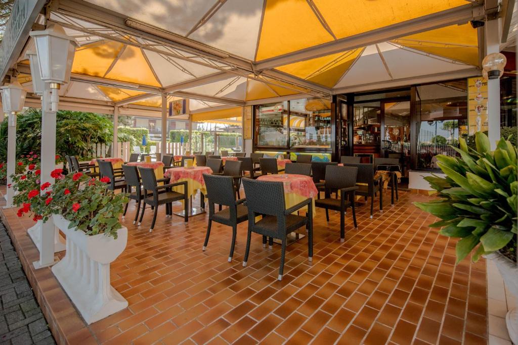 un restaurant avec des tables, des chaises et des fleurs dans l'établissement Park Hotel Perù ***S, à Lido di Jesolo