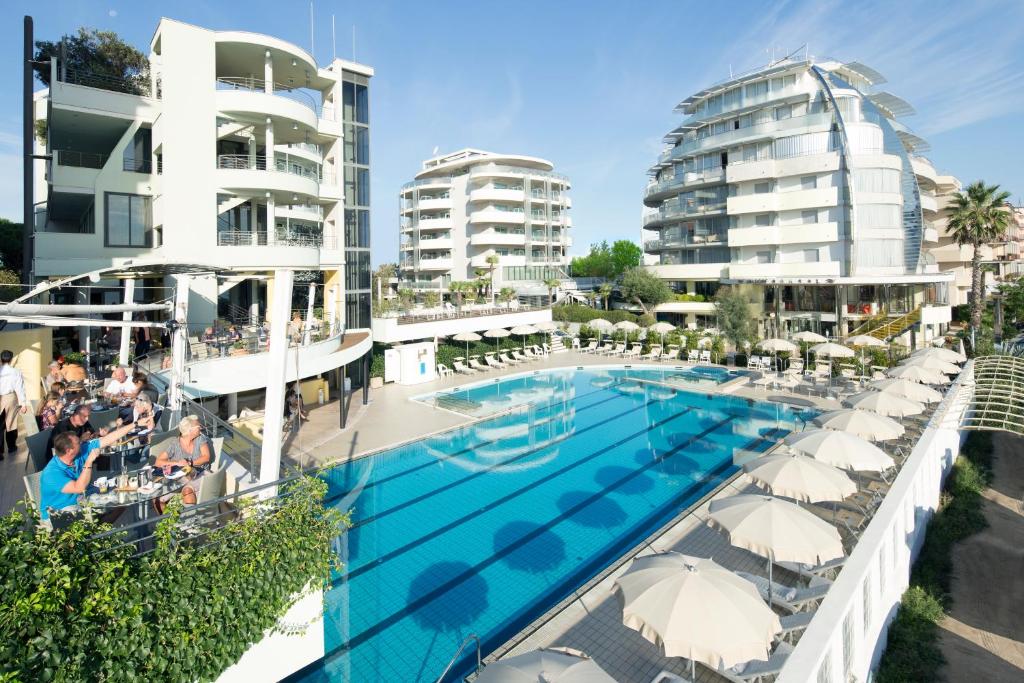 - une vue sur la piscine et les bâtiments dans l'établissement Hotel Le Palme - Premier Resort, à Milano Marittima