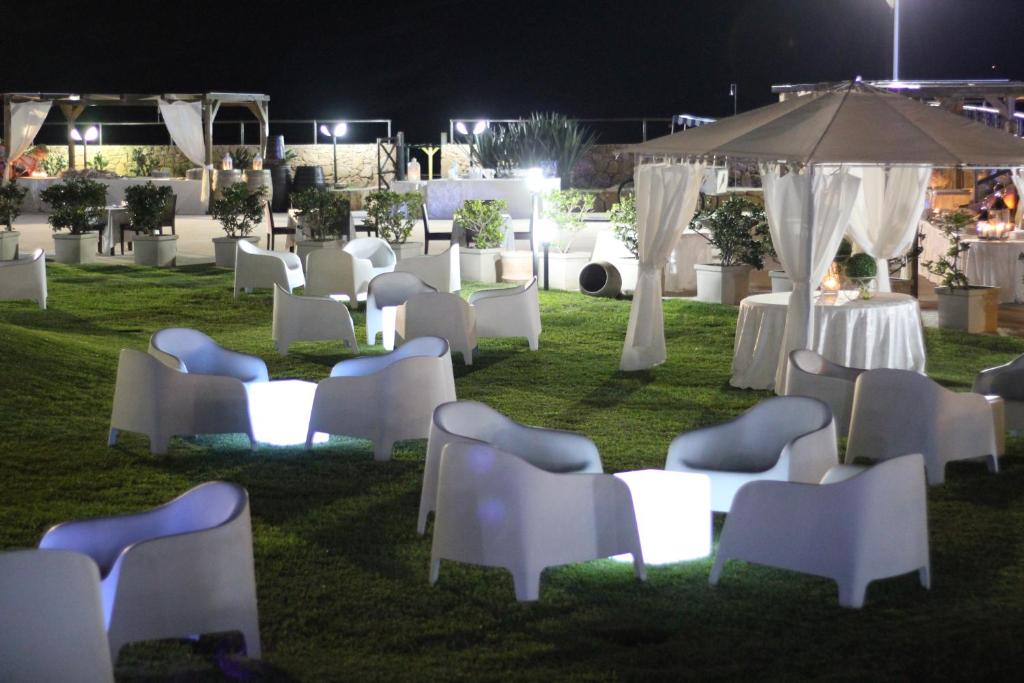un groupe de chaises et de tables dans un champ la nuit dans l'établissement Hotel Capo Campolato, à Brucoli 80 autres photos