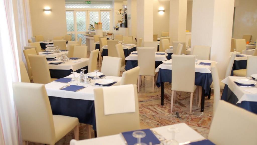 une salle à manger avec des tables et des chaises blanches dans l'établissement Family Hotel Antibes -50m dal mare -, à Riccione