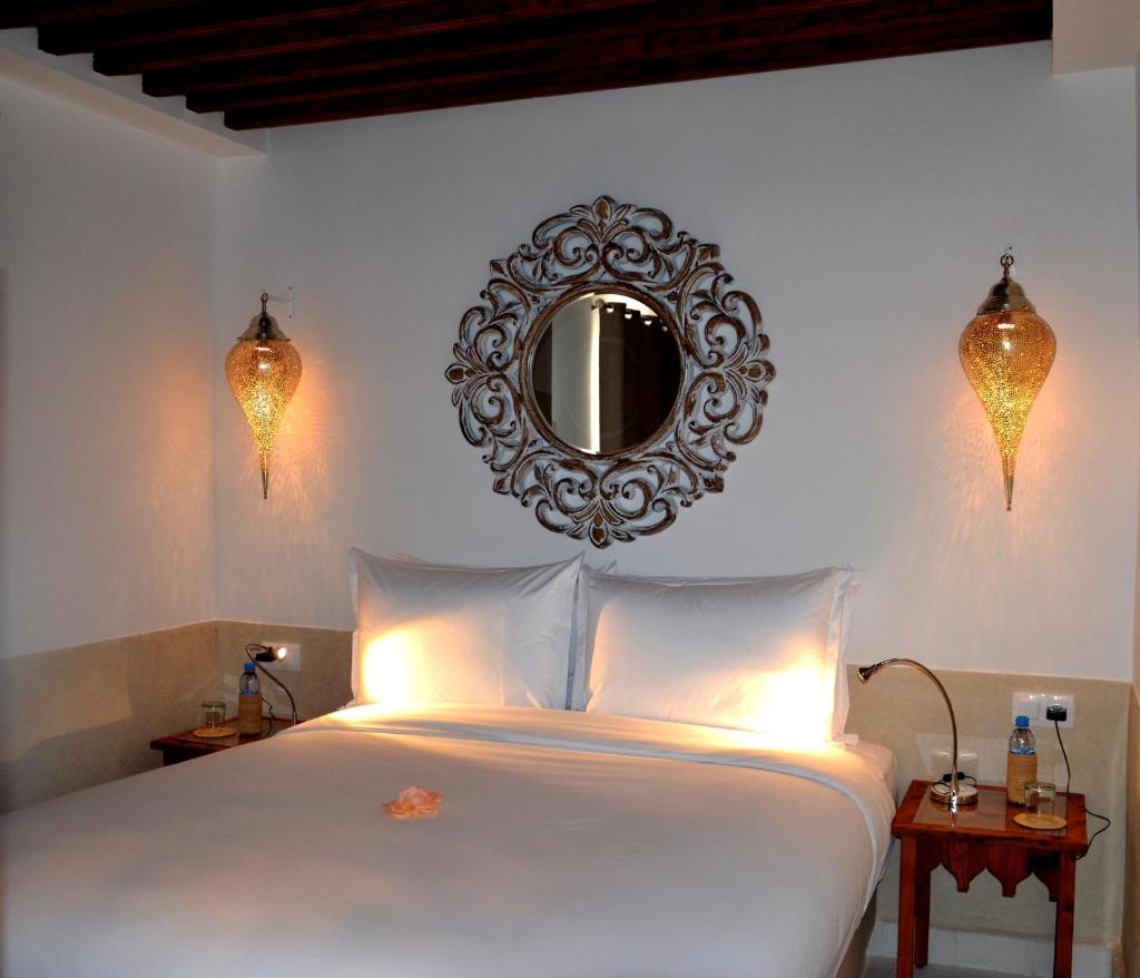 - une chambre avec un lit blanc et un miroir mural dans l'établissement Riad Dar Dar, à Rabat