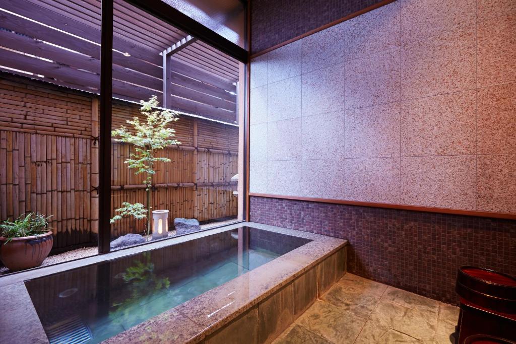 une baignoire dans une pièce avec une fenêtre dans l'établissement 旅館かわな -Ryokan Kawana-, à Kimitsu