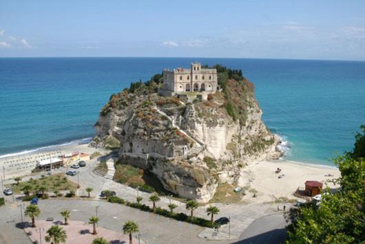 un bâtiment au sommet d'un rocher dans l'océan dans l'établissement Hotel Alexander, à Tropea