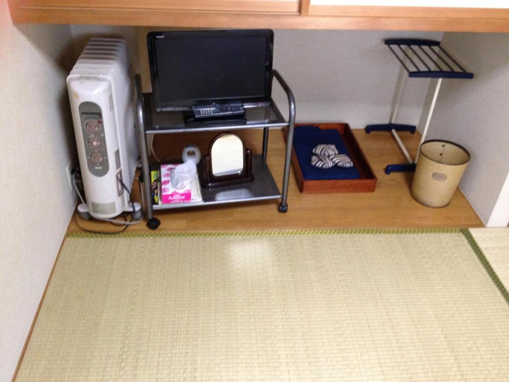 - un bureau avec un ordinateur portable et un ordinateur sur une étagère dans l'établissement Iroha Ryokan, à Aomori