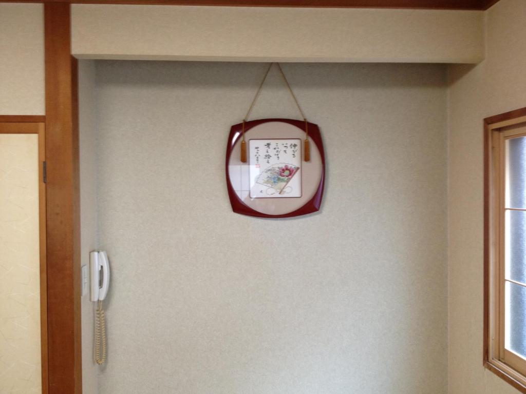 une horloge suspendue sur un mur à côté d'une porte dans l'établissement Iroha Ryokan, à Aomori