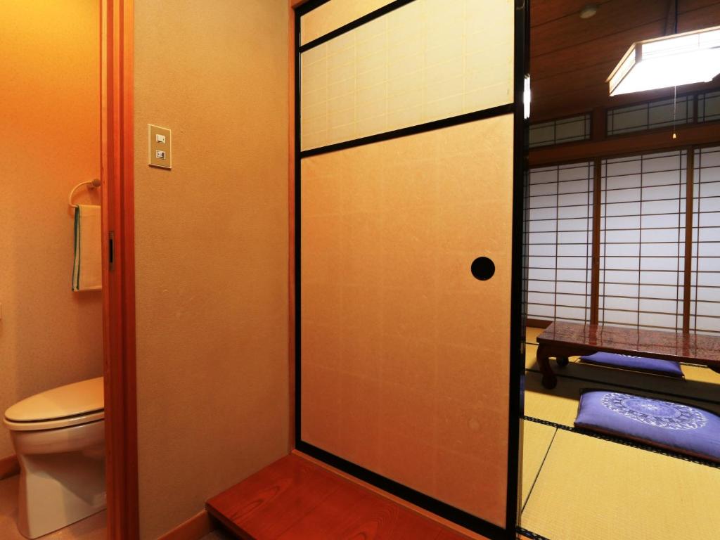 La salle de bains est pourvue de toilettes et d'une porte en verre. dans l'établissement Yunohirakan, à Takayama
