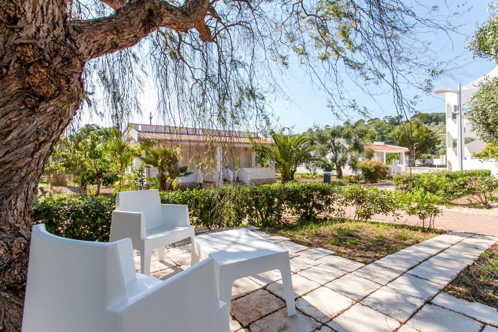 une table et des chaises blanches sous un arbre dans l'établissement Hotel Scialì, à Vieste