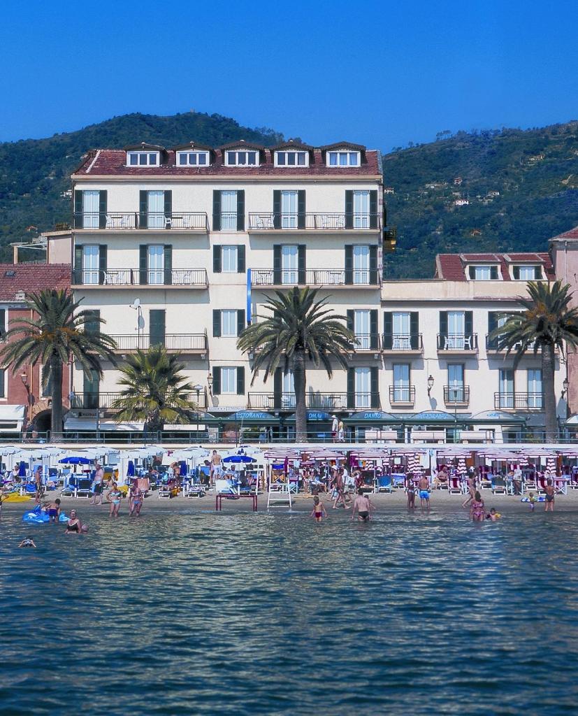 un groupe de personnes sur une plage en face d'un bâtiment dans l'établissement Hotel Danio Lungomare, à Alassio