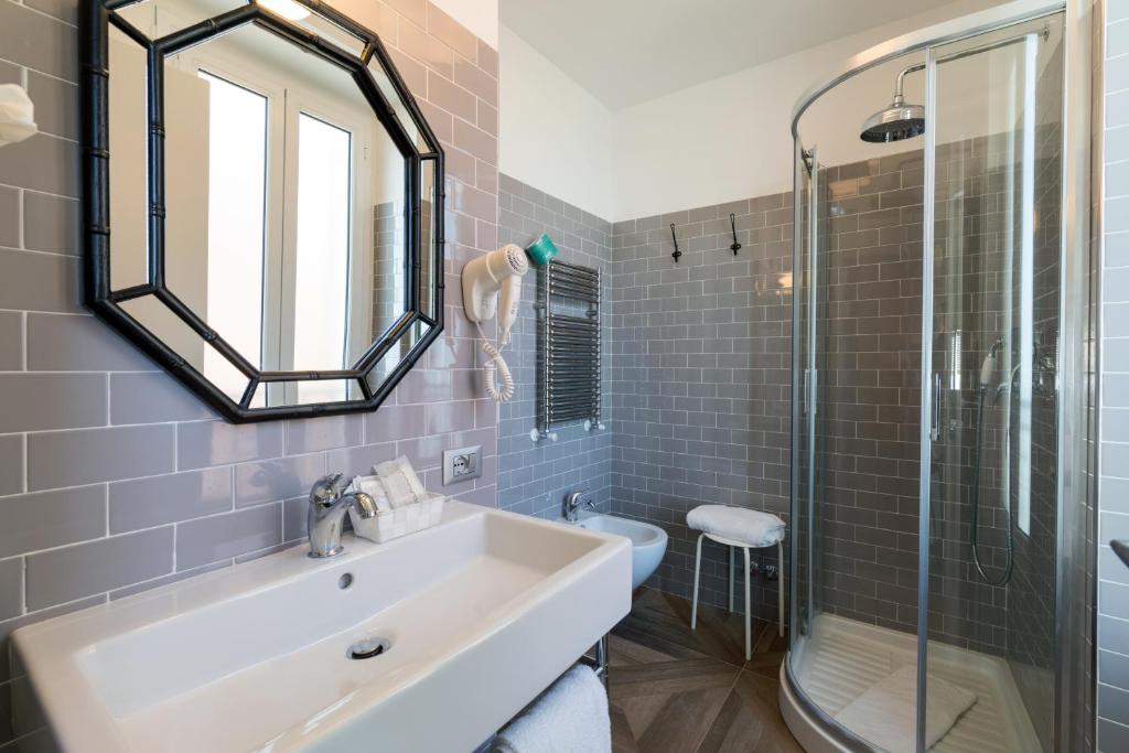 une salle de bain avec un lavabo, un miroir et une douche dans l'établissement Hotel Eden Alaxi Hotels, à Alassio