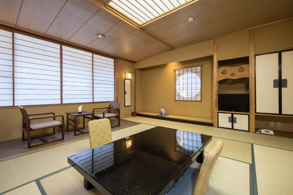 Cette grande chambre dispose d'une table, de chaises et de fenêtres. dans l'établissement Hotel Umenoyu, à Matsumoto