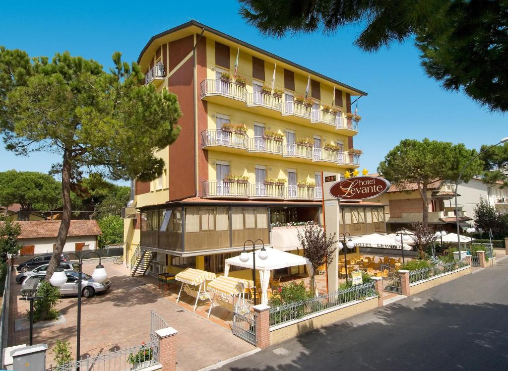 un grand bâtiment avec un café en face dans l'établissement Hotel Levante, à Cervia