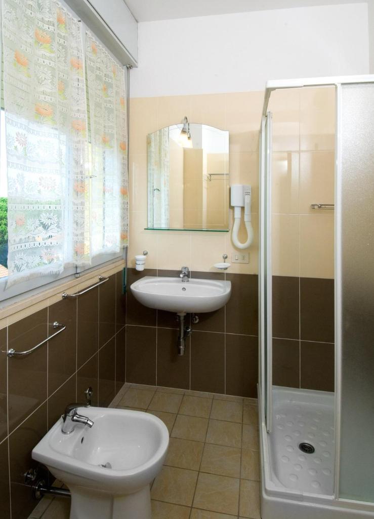 une salle de bain avec un lavabo, des toilettes et une douche dans l'établissement Hotel Levante, à Cervia