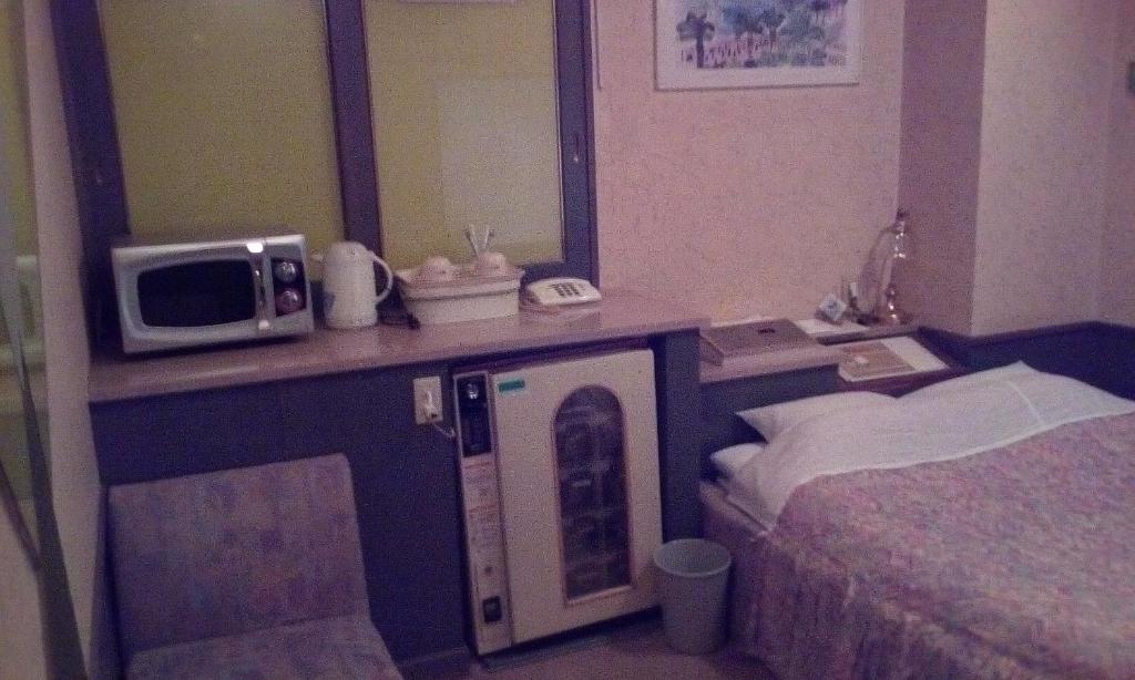 une chambre d'hôtel avec un lit et un four micro-ondes sur un comptoir dans l'établissement Hotel Ikoma (Love Hotel), à Nagasaki