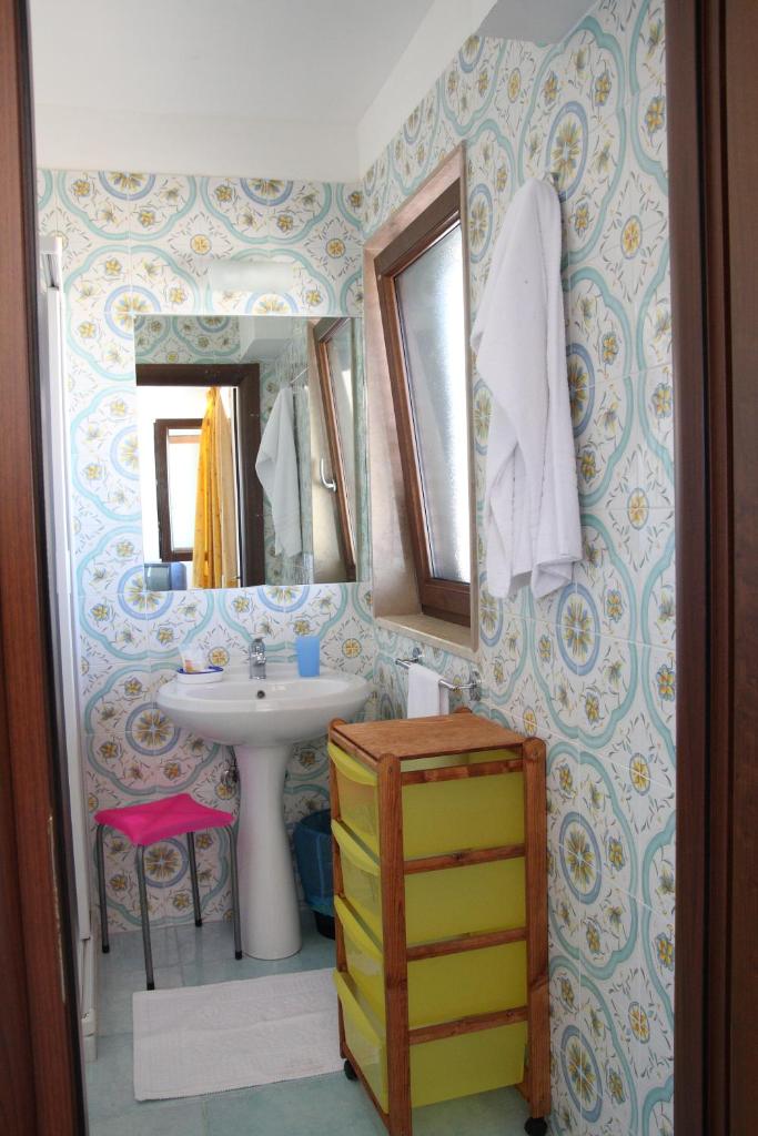 une salle de bain avec un lavabo et un miroir dans l'établissement Lido Impero, à Palagiano