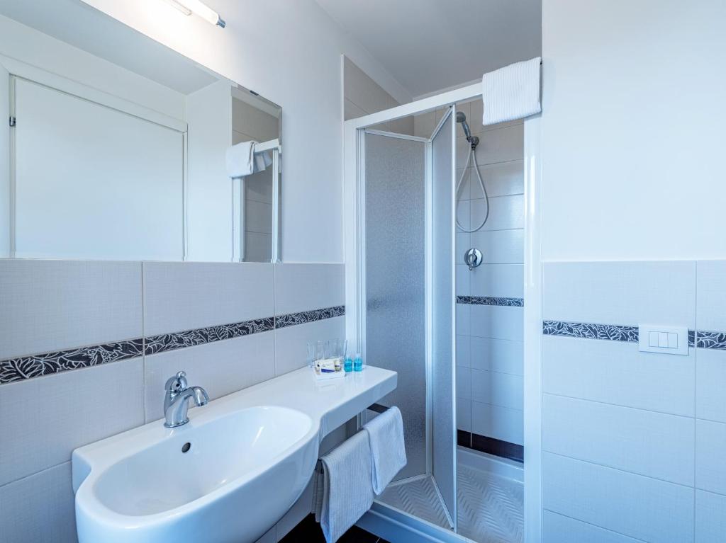 une salle de bain blanche avec lavabo et douche dans l'établissement Hotel Andreaneri, à Marina di Pietrasanta