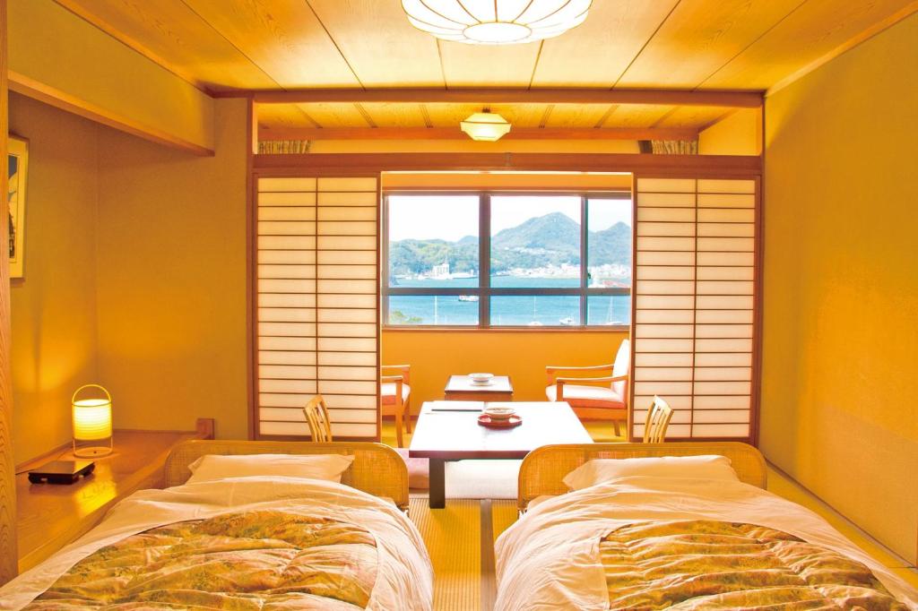 une chambre avec deux lits, une table et une fenêtre dans l'établissement Hotel Yamadaya, à Shimoda