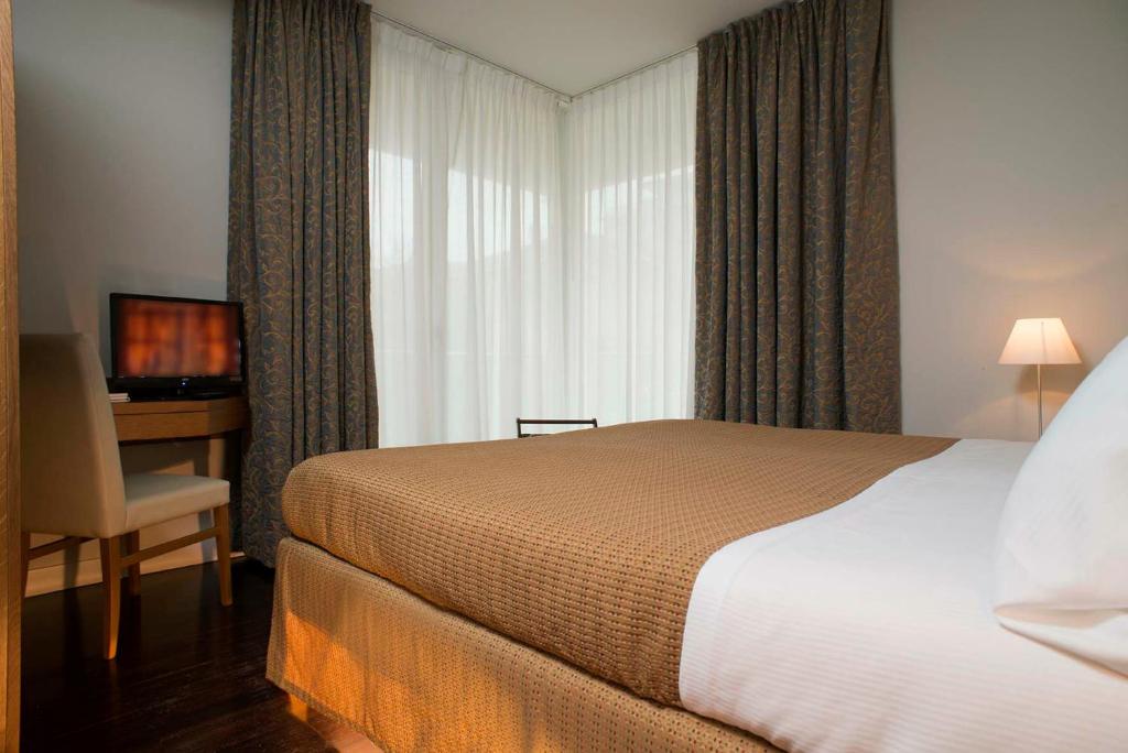 une chambre d'hôtel avec un lit, un bureau et une fenêtre dans l'établissement Villa dei Gelsomini & National Hotel dal 1903, à Rimini 12 autres photos