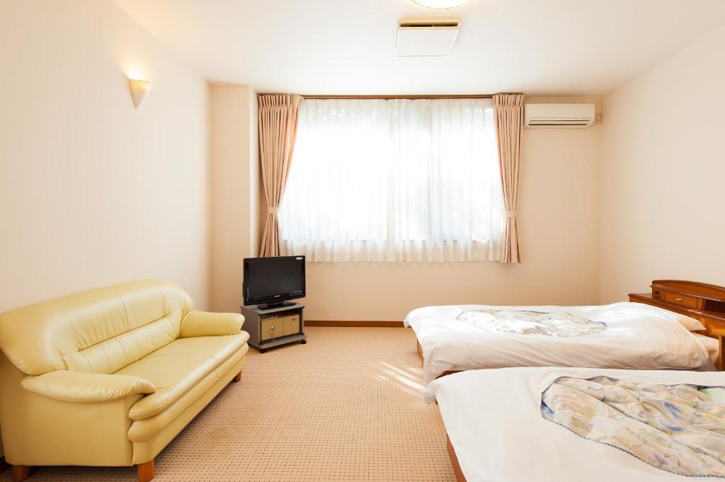 Cette chambre comprend deux lits, une chaise et une télévision. dans l'établissement Watarase Onsen Hotel Yamayuri, à Hongu